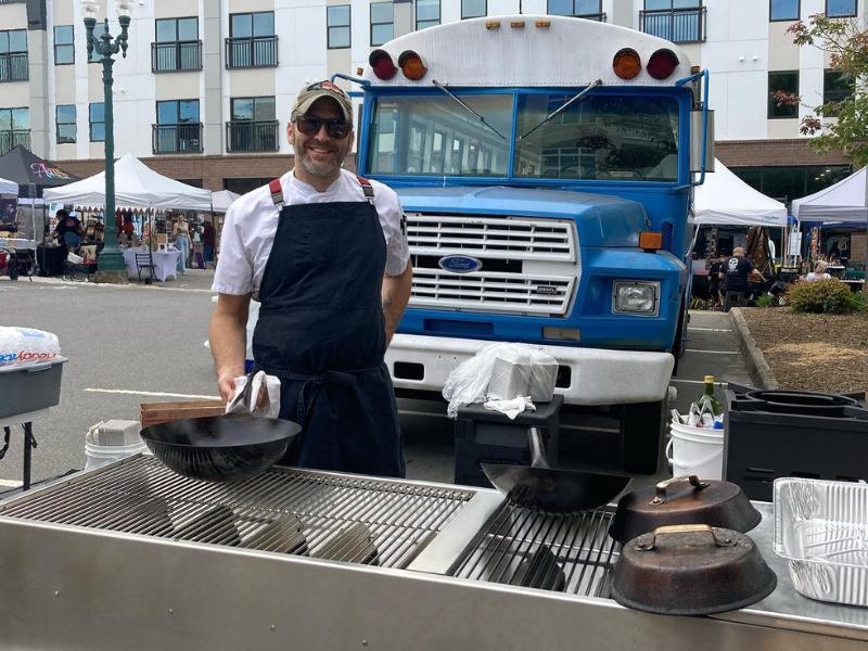 Chef Bob holding wok at street festival outdoor kitchen setup